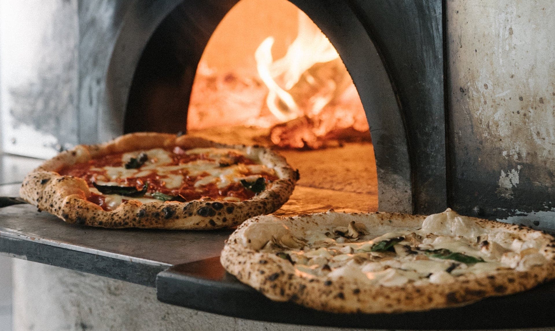 Horno a leña con dos pizzas saliendo